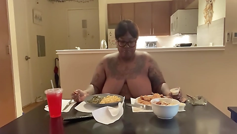 Slim ebony with a tattooed body is smoking a cigarette